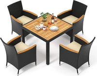 Modern rattan garden furniture set placed in a lush green backyard with soft lighting.