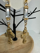 Small gold filigree cross earrings that are adorned with red green or clear rhinestones