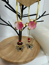 Gold 1 3/4 inch hoops with flower adornment and dangling butterfy